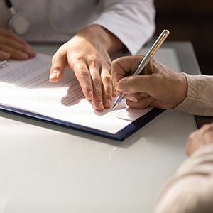 Senior signing documents with a doctor, related to naming a Trustee for an estate plan in New York law.
