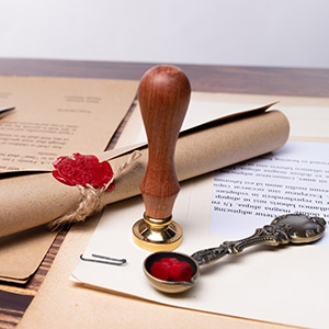 Vintage wax seal stamp and scroll on legal papers; protect your property with Lindenhurst lawyers.